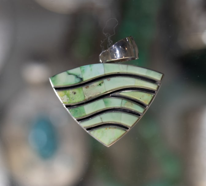 Green stone and silver pendant with a geometric wave design