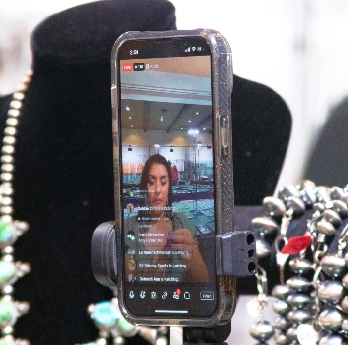 Smartphone livestreaming a jewelry display at an indoor event